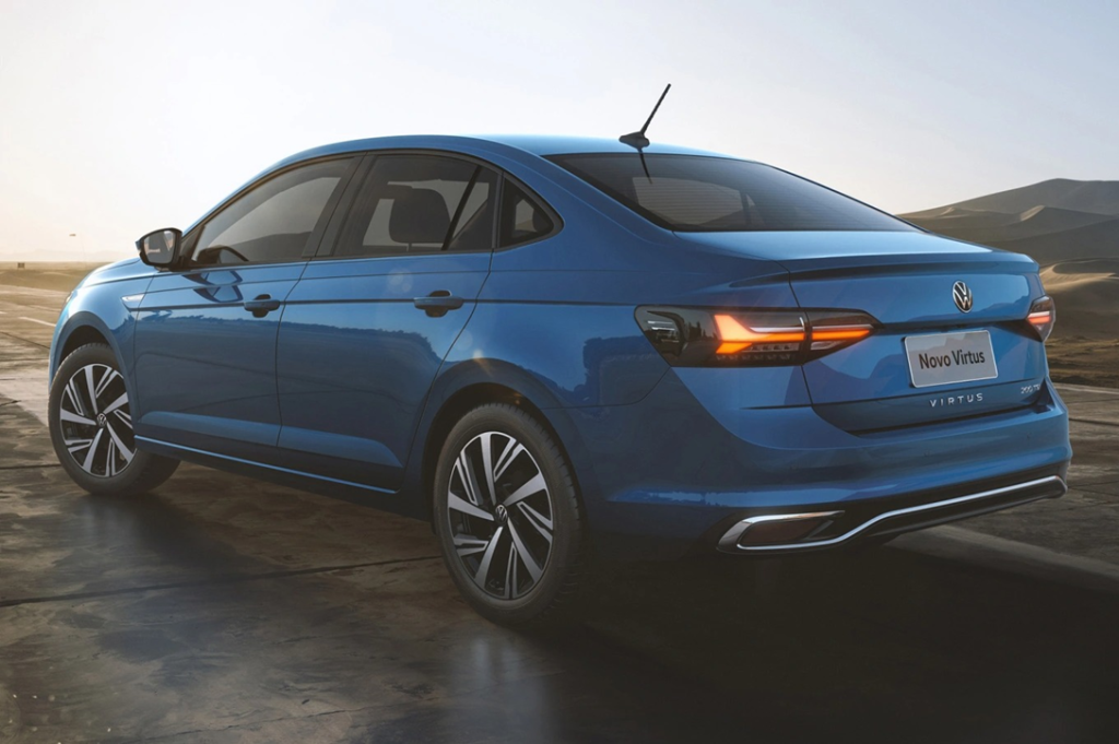 Traseira de um Volkswagen Virtus azul em movimento, em estrada aberta, destacando lanternas e design do sedã.