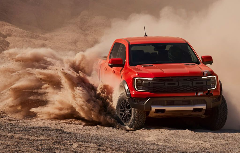 Ford Ranger vermelha em estrada de terra com muita poeira ao redor, em ambiente off-road.