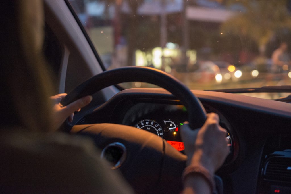 Woman holds the steering wheel of a car with two hands. Driving at night, commuting with an empty fuel tank