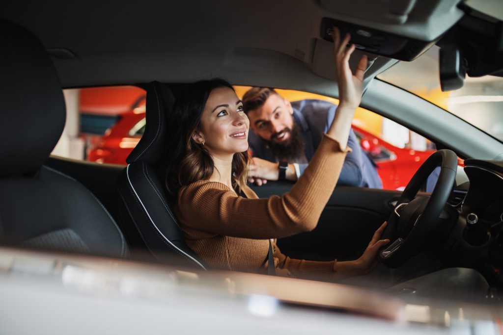 Happy young couple is buying a new car at the car showroom.