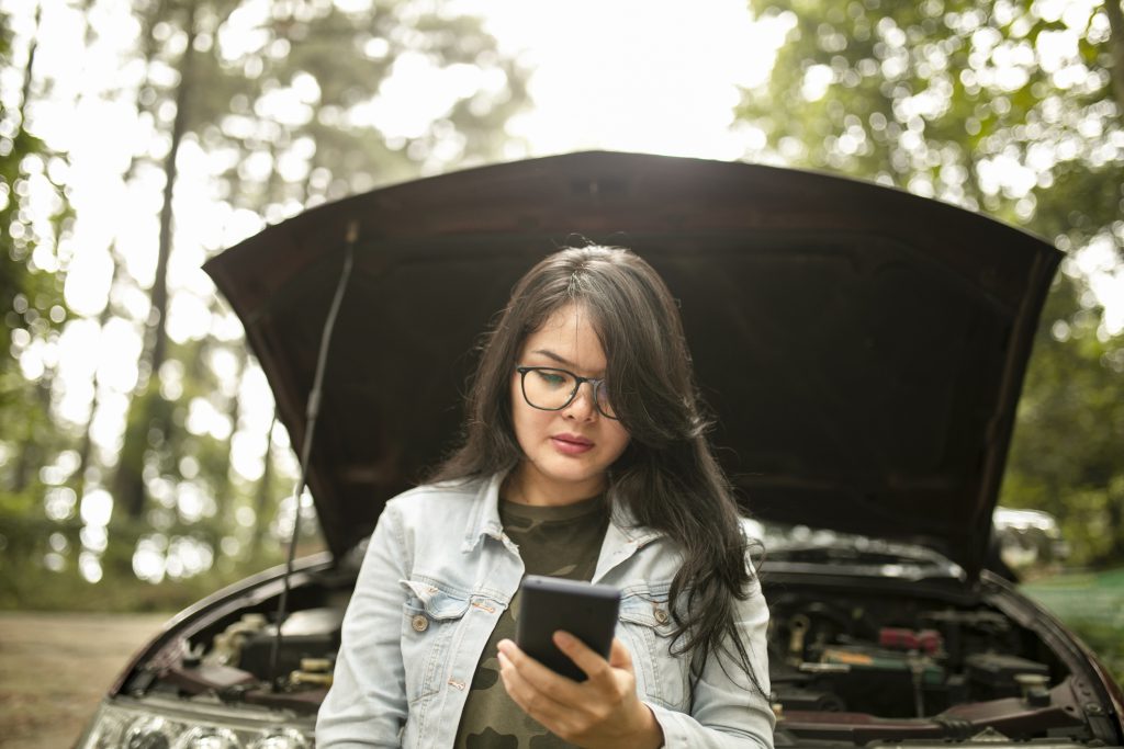 Asian Young, stressed woman is calling emergency service to help her with a broken car.