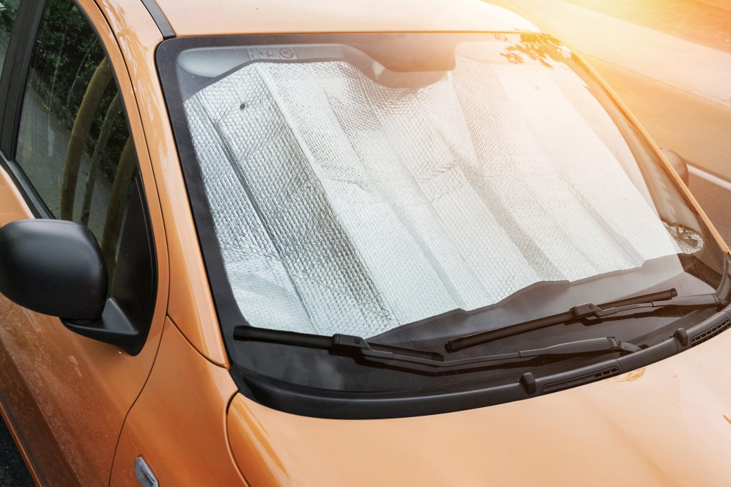 carro estacionado no sol com protetor no para-brisa para reduzir a temperatura interna