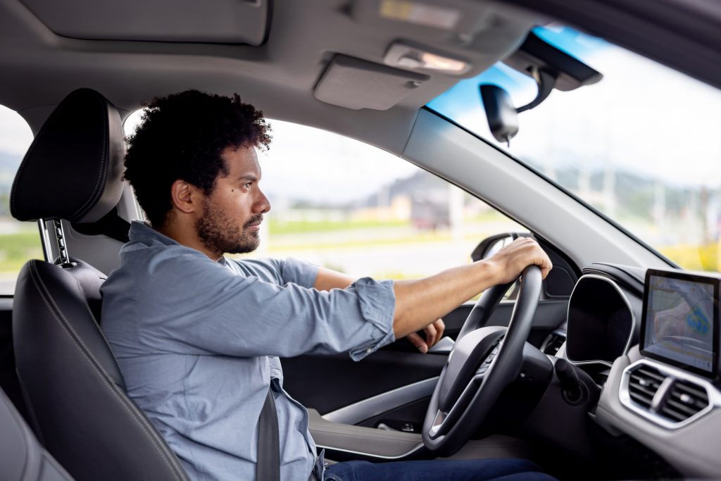 Profile view of a Latin American Man looking focused driving a car - mode of transport concepts