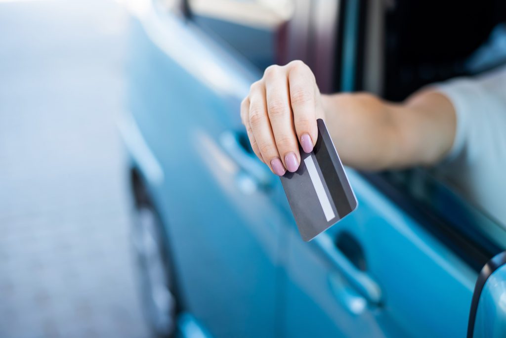 A woman pays with a credit card while refueling a car.