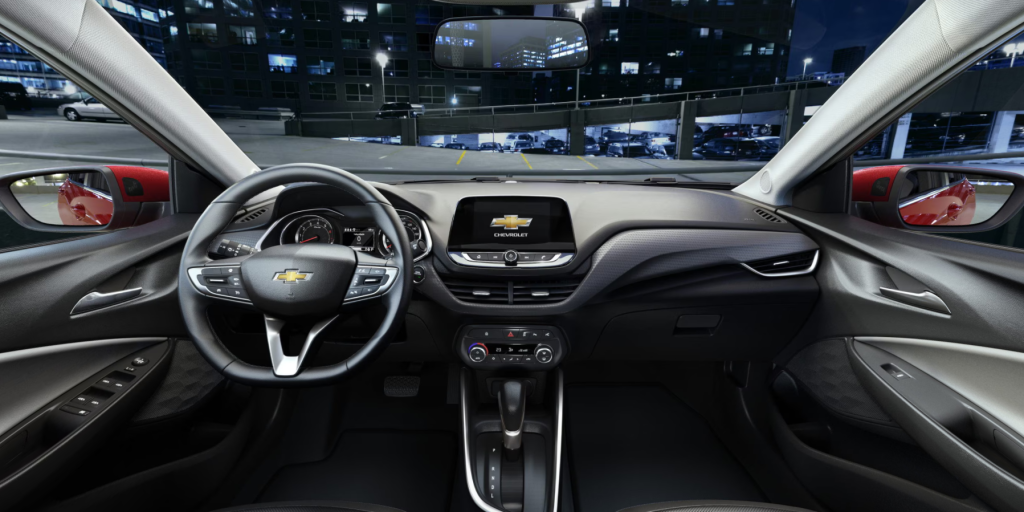 interior de um Chevrolet Onix com foco no painel central e volante, tela multimídia acesa exibindo o sistema Uconnect