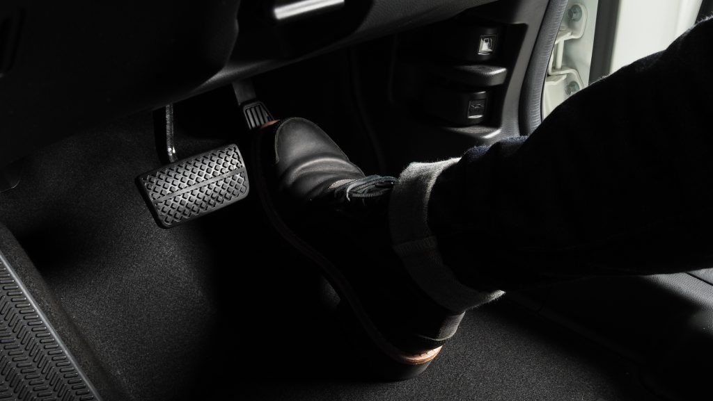 Pé pressionando o pedal da embreagem de um carro manual