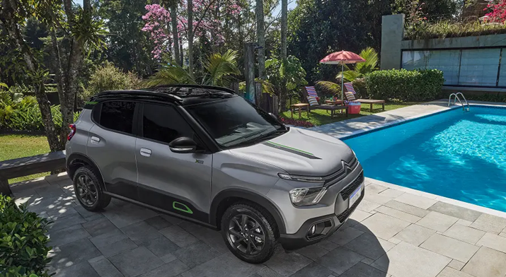carro Citroën C3 cinza estacionado ao lado de uma piscina, em um quintal ensolarado, com casa ao fundo, transmitindo atmosfera de lazer e conforto.