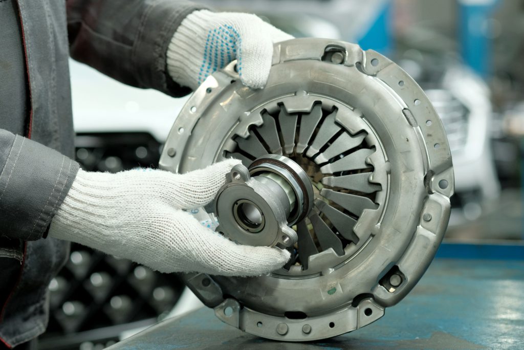 An auto mechanic checks the technical condition of the drive disc, the driven disc and the exhaust bearing. Repair and maintenance in a car service.
