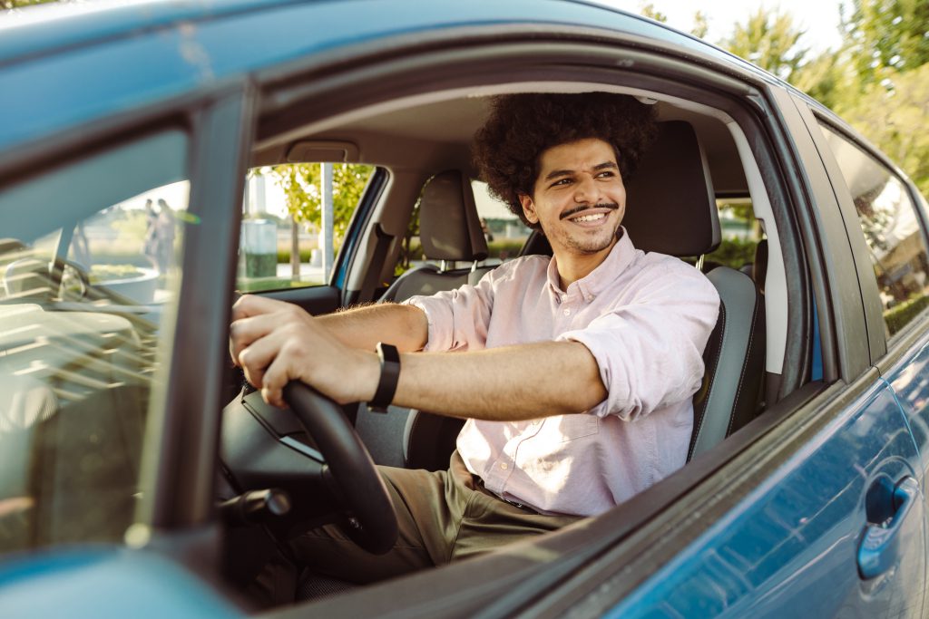 Photo of a young man holding the steering wheel in the car and smiling