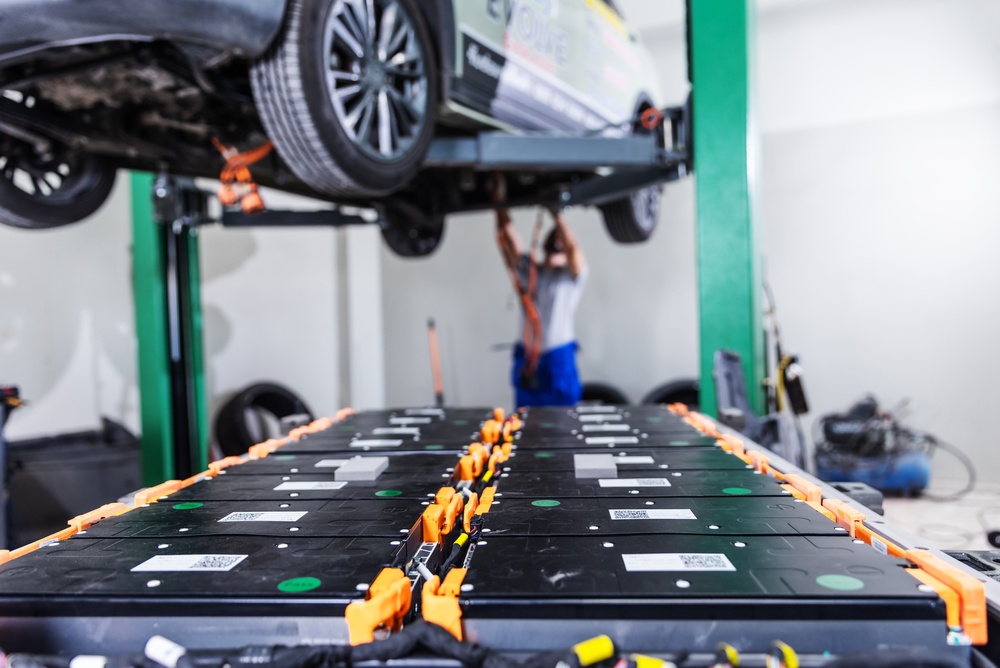 Bateria de alta tensão removida de um carro elétrico durante procedimento de manutenção.